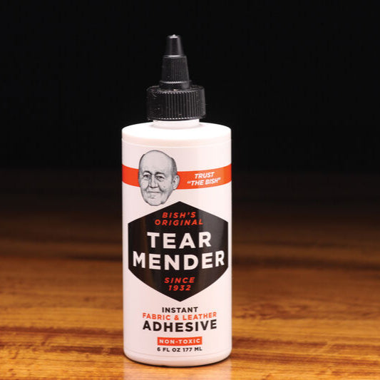 Bish's Tear Mender adhesive bottle on a wooden surface with a dark background